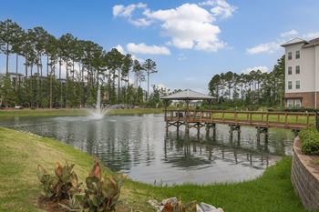 A fountain in the middle of a lake with a bridge in the background.